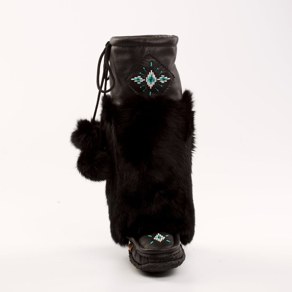 Black fur mukluks with decorative emblem on a white background