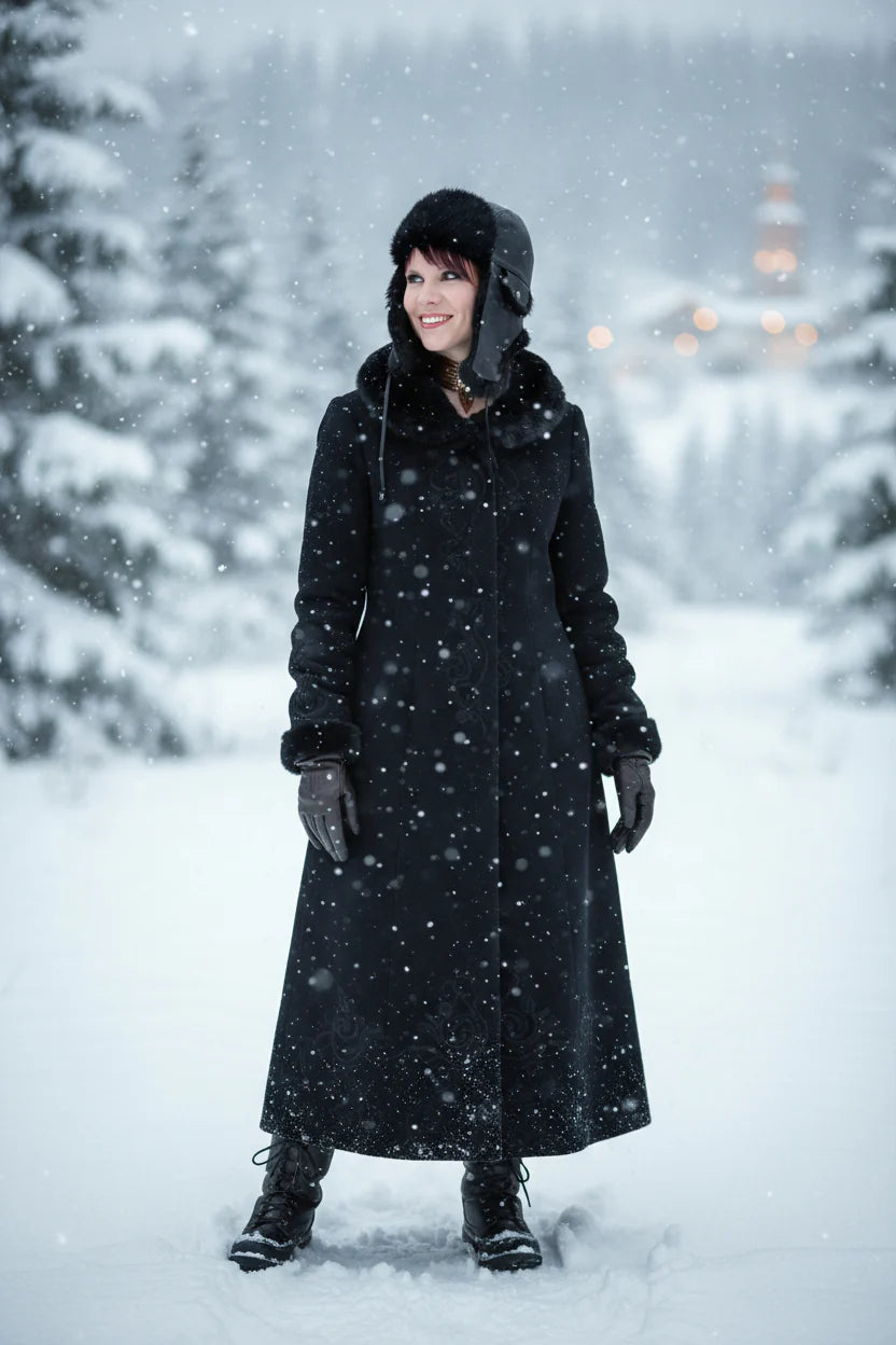 Person wearing a long black coat in a snowy forest