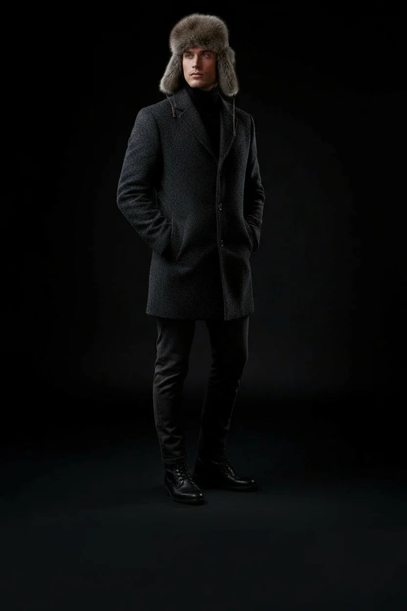 Man wearing a dark coat and fur hat against a black background