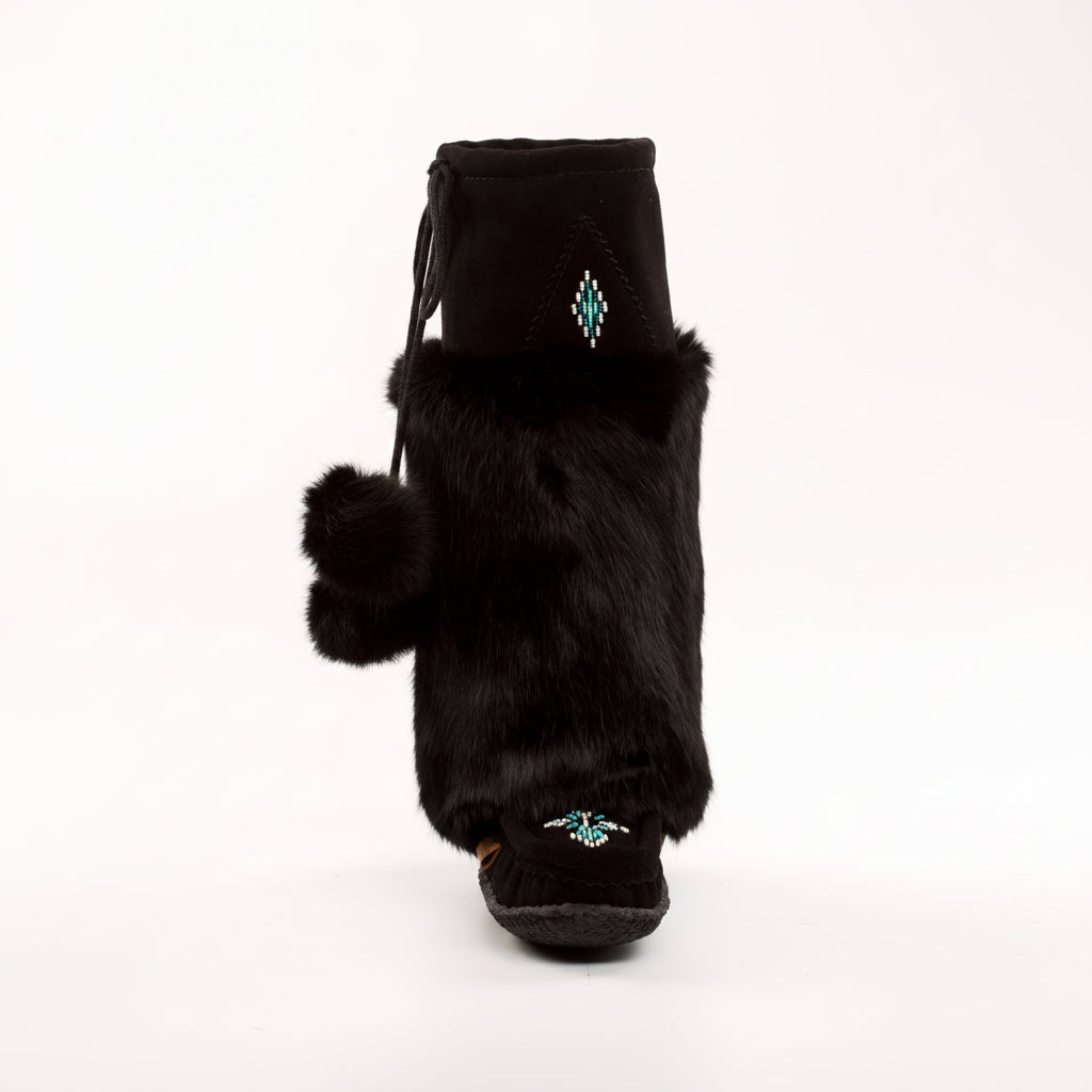Black furry boot with pom-pom details on a white background