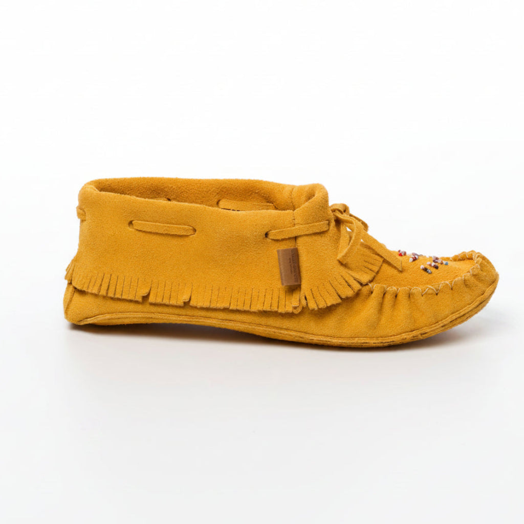 Yellow moccasin shoe with fringes on a white background