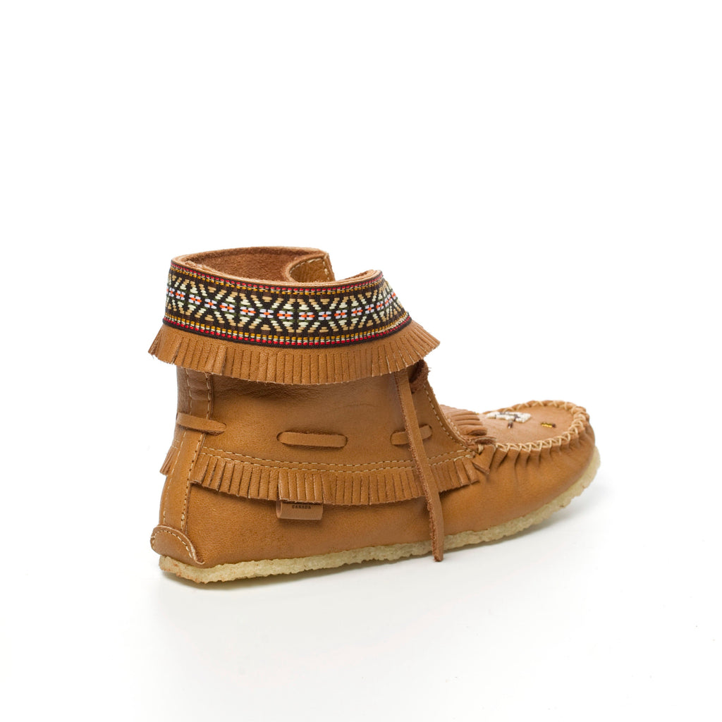 Tan moccasin boots with decorative band and fringes on a white background