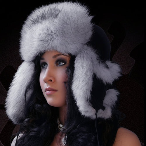 Woman wearing a gray fur hat with ear flaps against a dark background