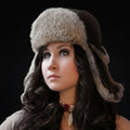 Woman wearing a fur-trimmed hat against a black background